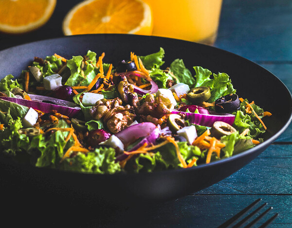 Schale mit Haferflocken, Beeren und Nüssen auf einem Holztisch